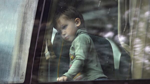 Девочка смотрит в окно автобуса перед отправкой беженцев их Донбасса в Россию