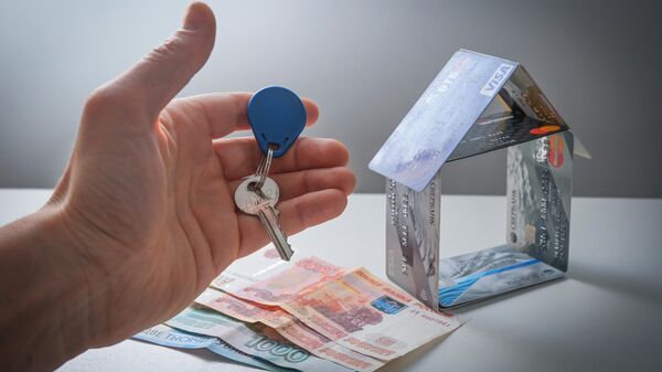 Ключ, деньги и домик, сложенный из банковских карт