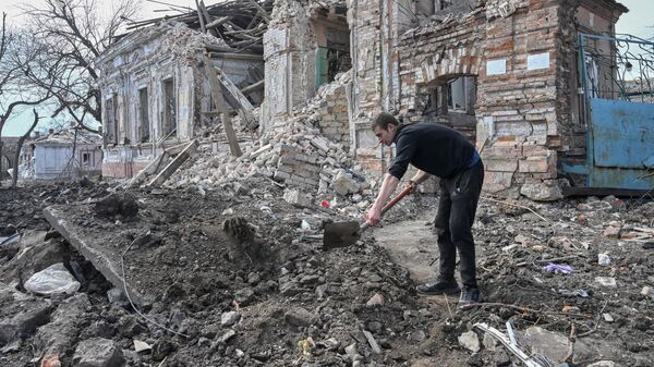 Житель Мариуполя расчищает проход к разрушенному зданию