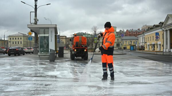 Сотрудник коммунальной службы моет тротуар на Кудринской площади в Москве