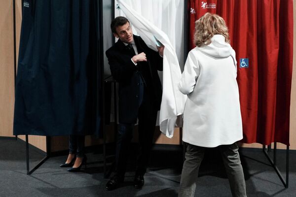 Президент Франции Эммануэль Макрон покидает кабинку для голосования во время первого тура президентских выборов