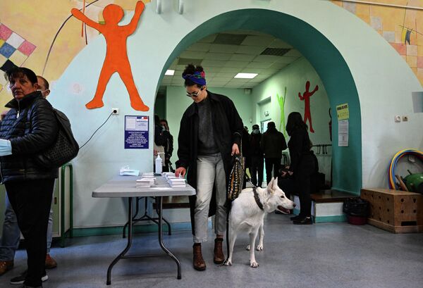 Женщина берет бюллетень для голосования в первом туре президентских выборов во Франции на избирательном участке в Марселе