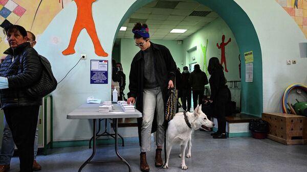 Женщина берет бюллетень для голосования в первом туре президентских выборов во Франции на избирательном участке в Марселе
