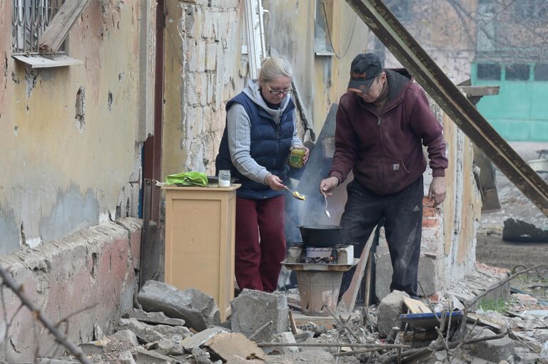 Жители Левобережного района Мариуполя готовят еду на костре возле подъезда дома