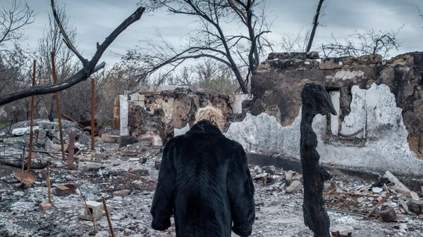Женщина у разрушенного дома в поселке Саханка Донецкой области.