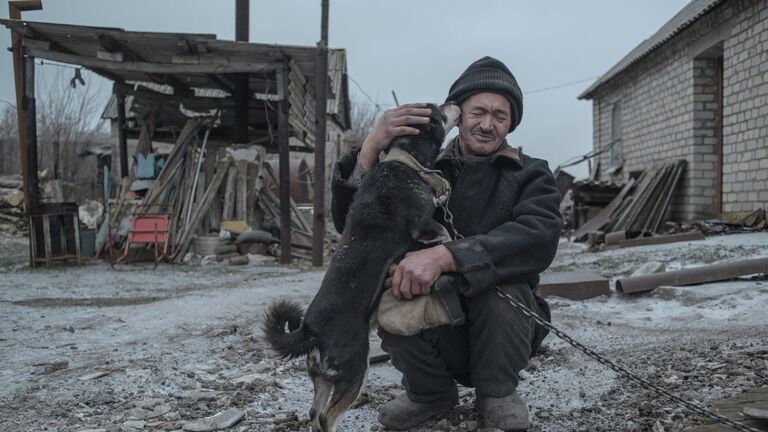 62-летний Александр Васильев со своей собакой - один из последних жителей поселка Новомарьевка Донецкой области.