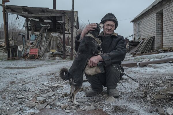 62-летний Александр Васильев со своей собакой - один из последних жителей поселка Новомарьевка Донецкой области.