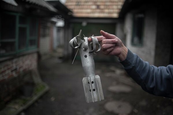Женщина демонстрирует осколок мины во дворе жилого дома в поселке Зайцево Донецкой области.