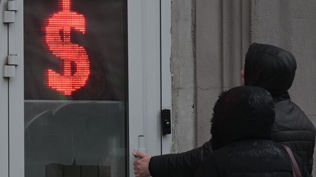Люди у входа в обменный пункт на одной из улиц в Москве