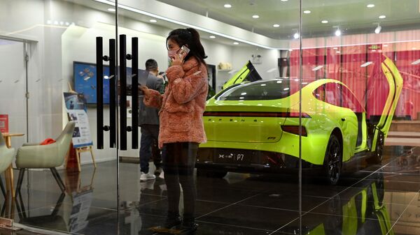 Женщина говорит по телефону в автосалоне Xiaopeng Motor, китайского производителя электромобилей, Пекин