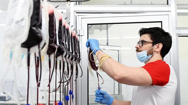 Медицинский сотрудник развешивает пакеты с кровью, сданной донорами