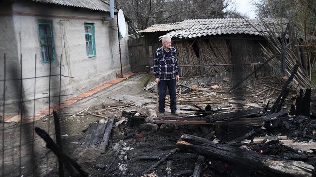 Мужчина во дворе жилого дома, пострадавшего в результате обстрела, в ЛНР