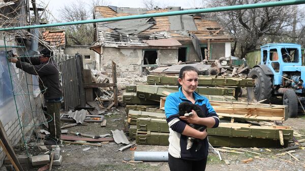 Женщина во дворе жилого дома, пострадавшего в результате обстрела, в населенном пункте Фрунзе в ЛНР
