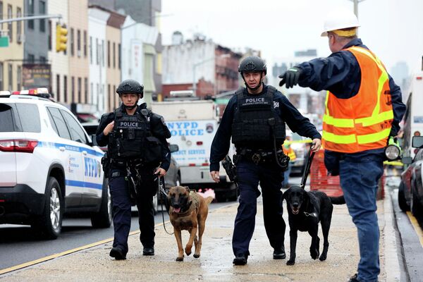 Сотрудники полиции с собаками осматривают местность возле станции метро в Нью-Йорке, где произошла стрельба