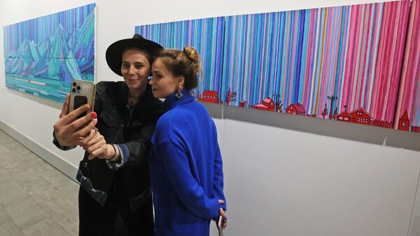 Посетители фотографируются на фоне картины, представленной на международной художественной ярмарке Арт Москва в выставочном центре Гостиный двор в Москве