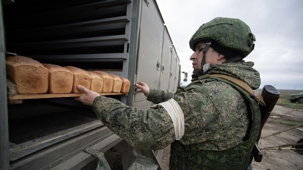 Военнослужащий ВС РФ грузит поддоны с выпеченным в мобильной пекарне хлебом в Херсонской области