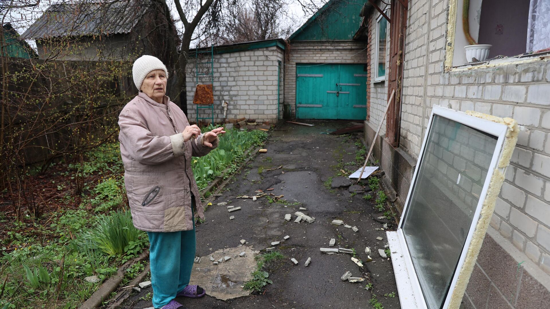 Женщина показывает свой дом, обстрелянный из РСЗО Град ВСУ, в Ясиноватой - РИА Новости, 1920, 14.04.2022