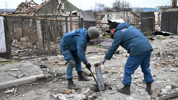 Сотрудники МЧС ДНР извлекают хвостовик ракеты реактивной системы залпового огня Град в Донбассе