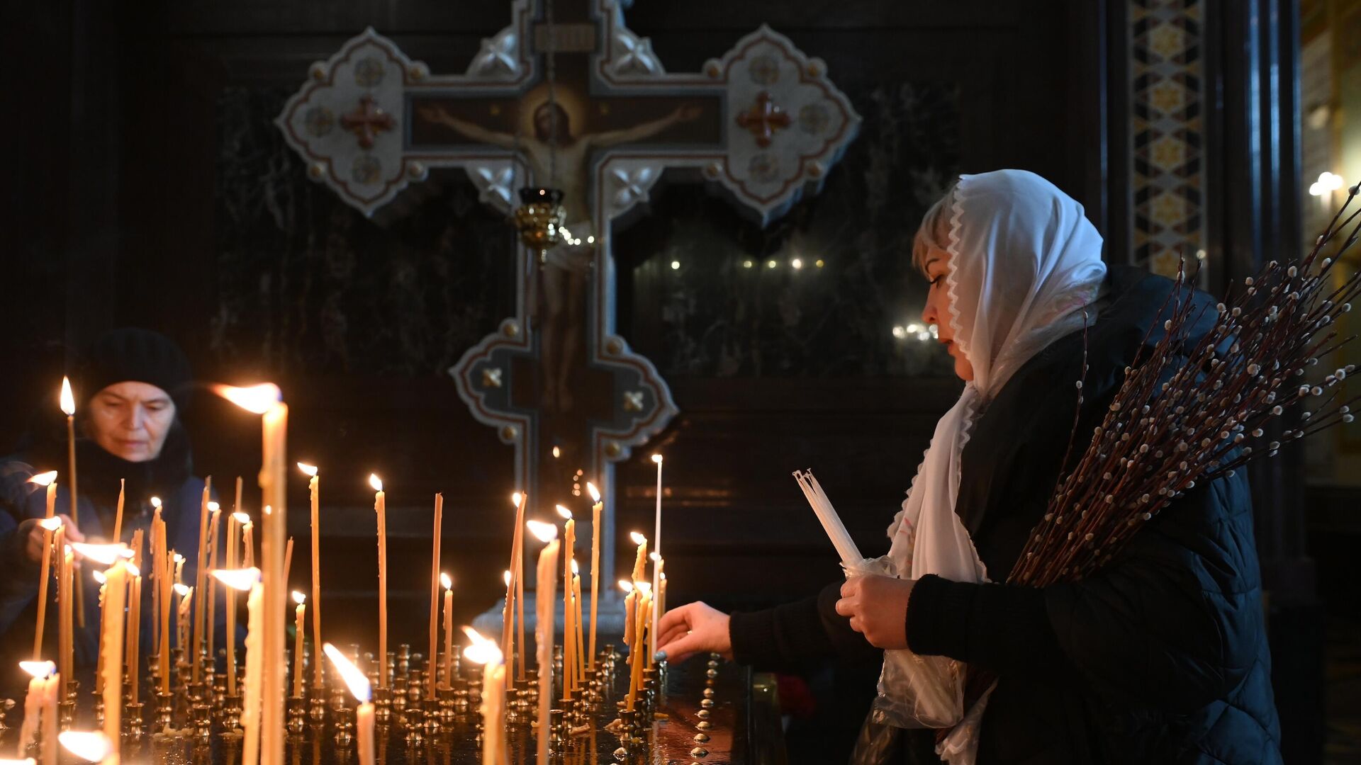 Женщина ставит свечу в праздник Вербного воскресенья в храме Христа Спасителя в Москве - РИА Новости, 1920, 27.05.2022