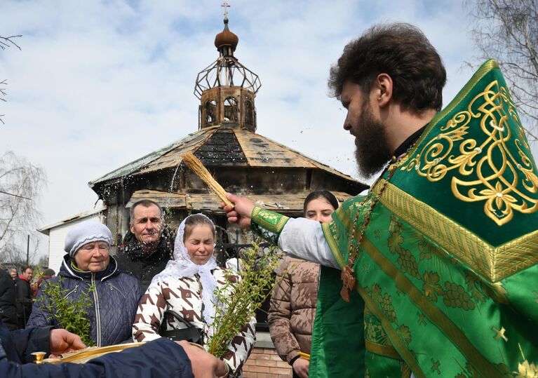 Верующие и отец Александр у пострадавшего во время боевых действий Свято-Преображенского храма в Волновахе, в день празднования Входа Господня в Иерусалим