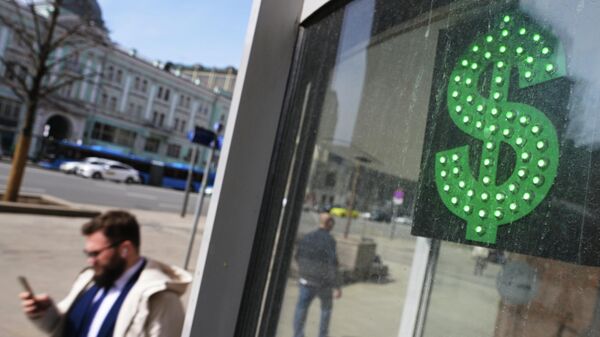 Мужчина проходит мимо пункта обмена валют со знаком доллара на одной из улиц в Москве
