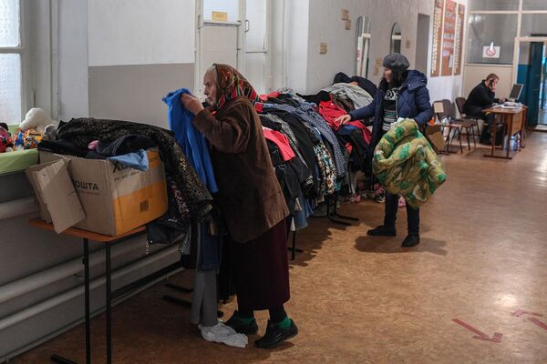 Беженцы из Рубежного выбирают одежду в пункте временного размещения в лицее №2 города Старобельска