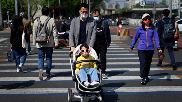Мужчина с детской коляской переходит улицу в Пекине
