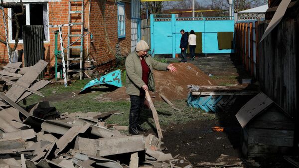 Женщина во дворе жилого дома частично разрушенного в результате обстрела ВСУ села Головчино в Белгородской области