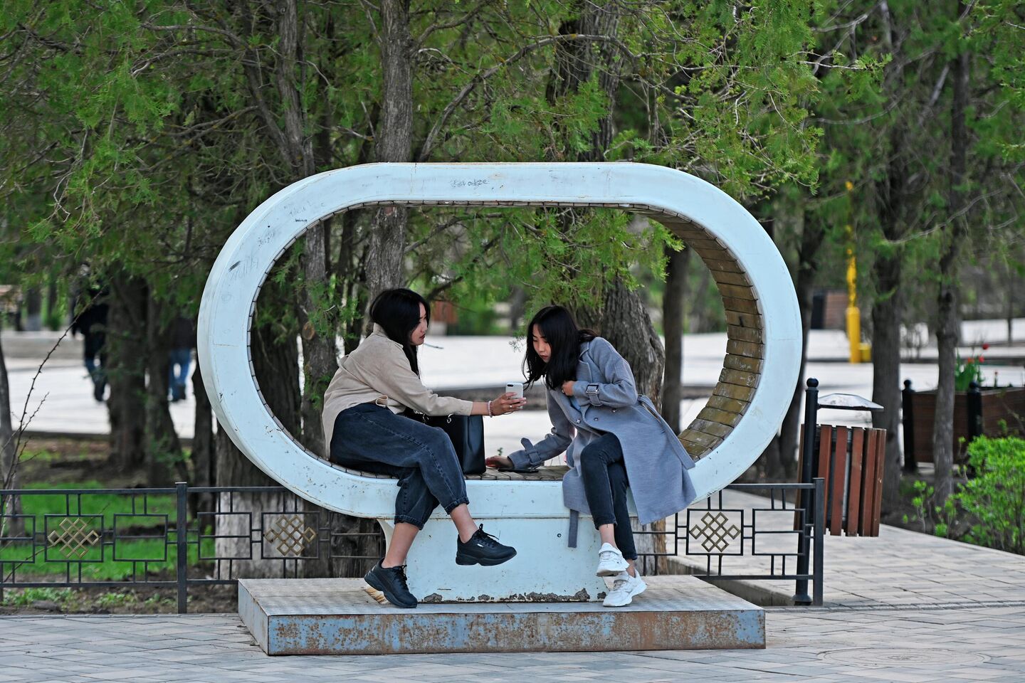 Девушки на скамейке, установленной на Аллее героев в центре Элисты