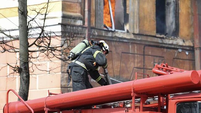 Сотрудник пожарной службы тушит пожар в здании Центрального научно-исследовательского института войск Воздушно-космической обороны в Твери