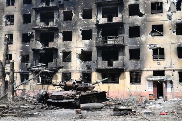 Разрушенный дом и остатки сгоревшего танка в Левобережном районе Мариуполя