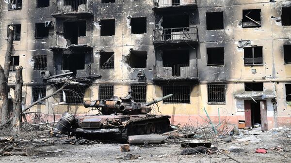 Разрушенный дом и остатки сгоревшего танка в Левобережном районе Мариуполя