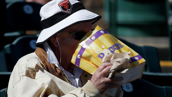 Мужчина ест попкорн перед весенним тренировочным бейсбольным матчем в Скоттсдейле