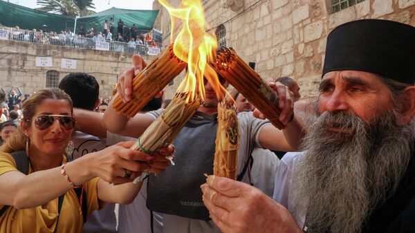 Верующие зажигают свечи во дворе иерусалимского храма Гроба Господня 