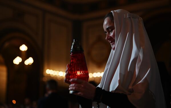 Монахиня несет лампаду с огнем во время пасхального богослужения в храме Христа Спасителя в Москве
