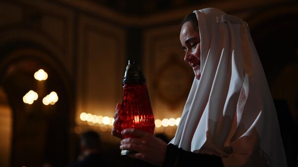 Монахиня несет лампаду с огнем во время пасхального богослужения в храме Христа Спасителя в Москве