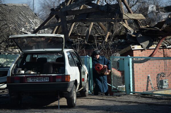 Женщина выносит вещи из своего разрушенного дома в поселке Октябрьский рядом с аэропортом города Донецка.