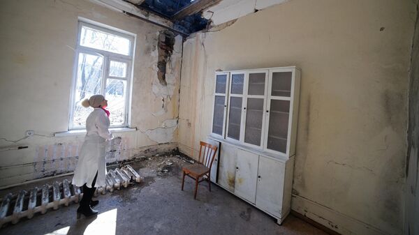 Сотрудница осматривает повреждения после обстрела в больнице в Донецке