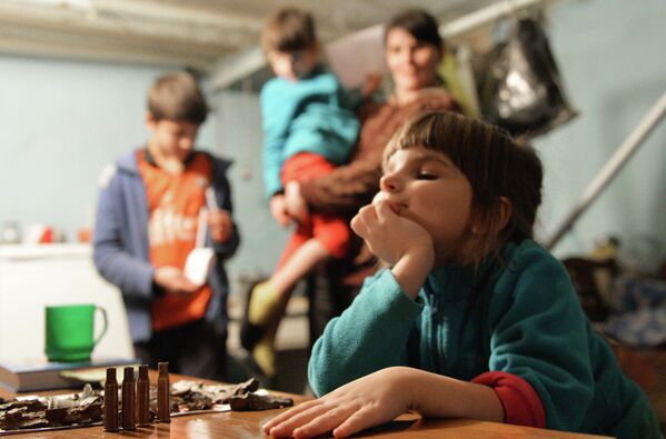 Девочка играет автоматными гильзами в подвале 21-й городской больницы, где она живет с родителями после того, как артиллерия украинской армии разрушила дом ее семьи в Донецке. 2014 год.