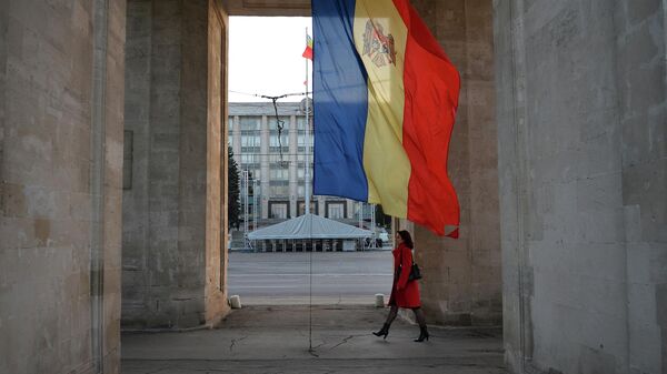 Девушка идет под триумфальной аркой рядом с флагом Молдавии в Кишиневе