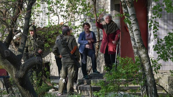 Местные жители и российские военнослужащие возле подъезда жилого дома в городе Рубежное Луганской народной республики