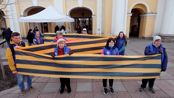 Волонтеры Победы держат георгиевскую ленточку в форме знака Z на одной из улиц Санкт-Петербурга в рамках ежегодной акции Георгиевская ленточка, посвященной 77-й годовщине Победы в Великой Отечественной войне