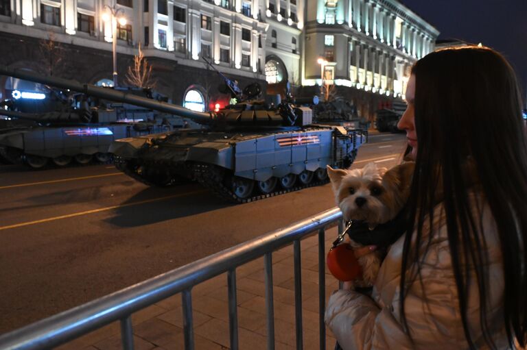 Девушка наблюдает за военной техникой на Тверской улице в Москве перед началом ночной репетиции военного парада к 77-й годовщине Победы в Великой Отечественной войне. На втором плане – танк Т-72Б3М