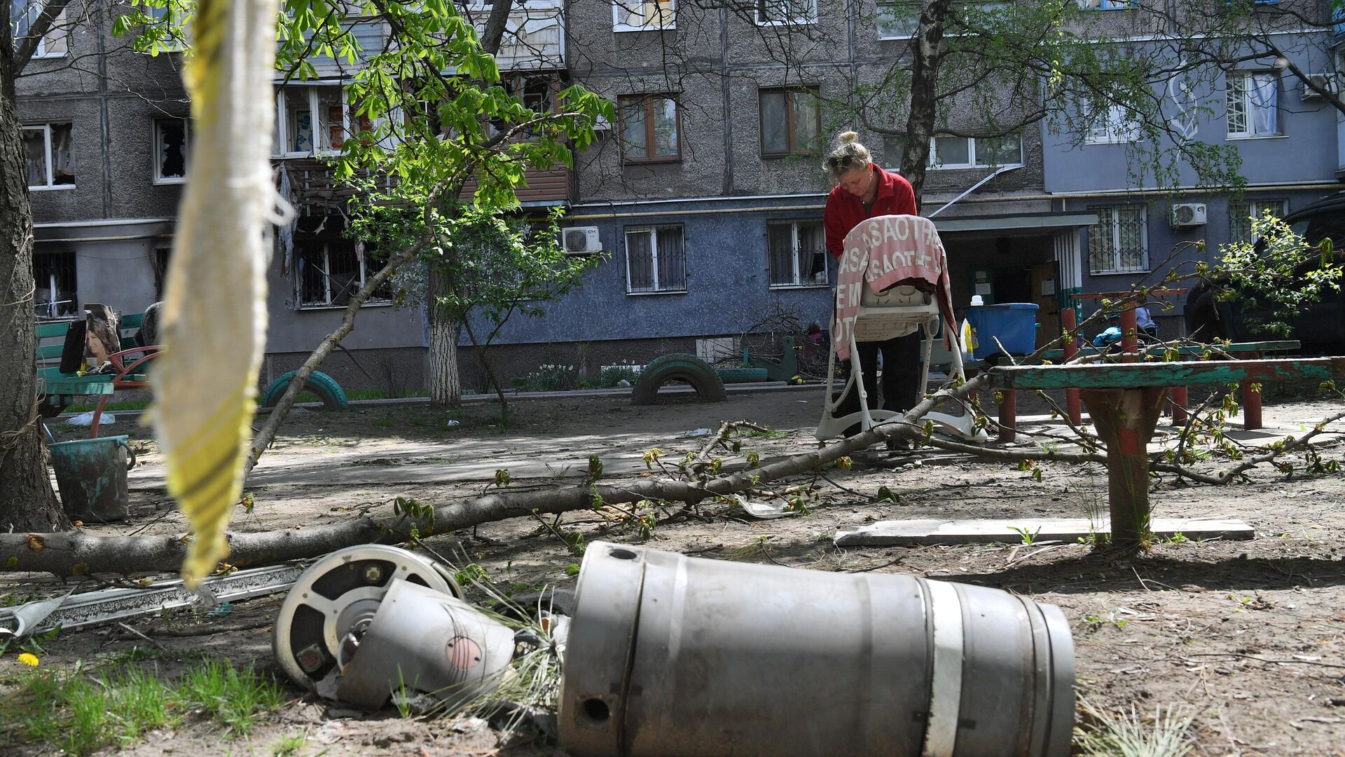 Жительница стирает одежду во дворе разрушенного дома в Левобережном районе Мариуполя - РИА Новости, 1920, 30.04.2022