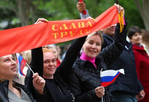 Участники первомайской демонстрации в Волгограде несут баннер с надписью Слава труду