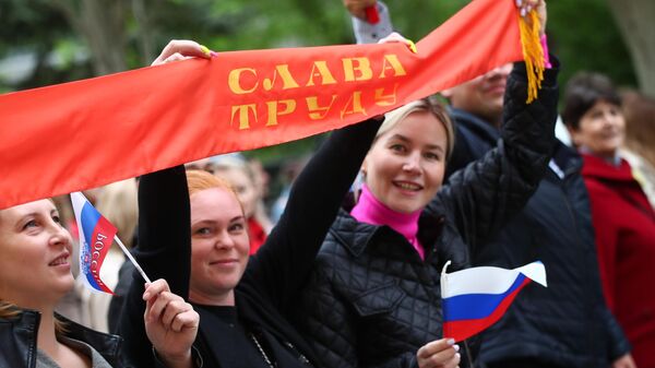 Участники первомайской демонстрации в Волгограде несут баннер с надписью Слава труду