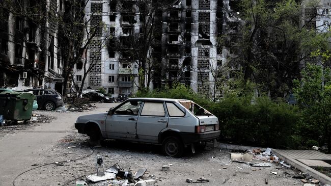 Поврежденные автомобили во дворе жилого дома в Мариуполе