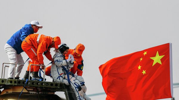 Космонавту помогают покинуть капсулу космического корабля Шэньчжоу-13 после приземления