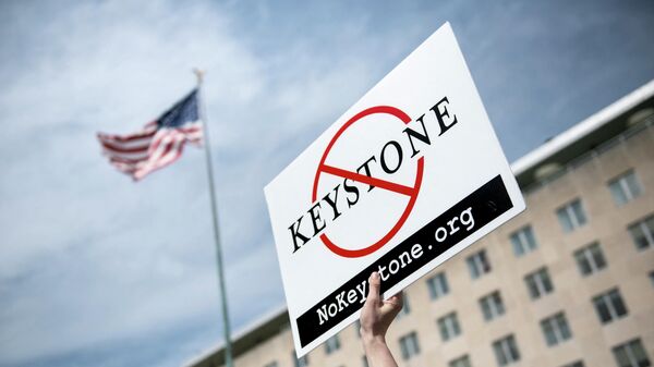 Активист держит табличку возле Государственного департамента во время акции протеста против строительства трансграничного нефтепровода Keystone XL , Вашингтон
