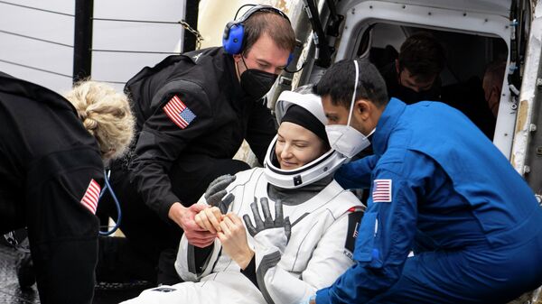 Астронавту НАСА Кайле Бэррон помогают выбраться из космического корабля SpaceX Crew Dragon